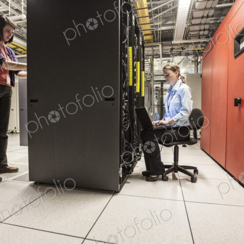 Caucasian women technicians working on computer servers in a server farm. Caucasian women technicians working on computer servers in a server farm.