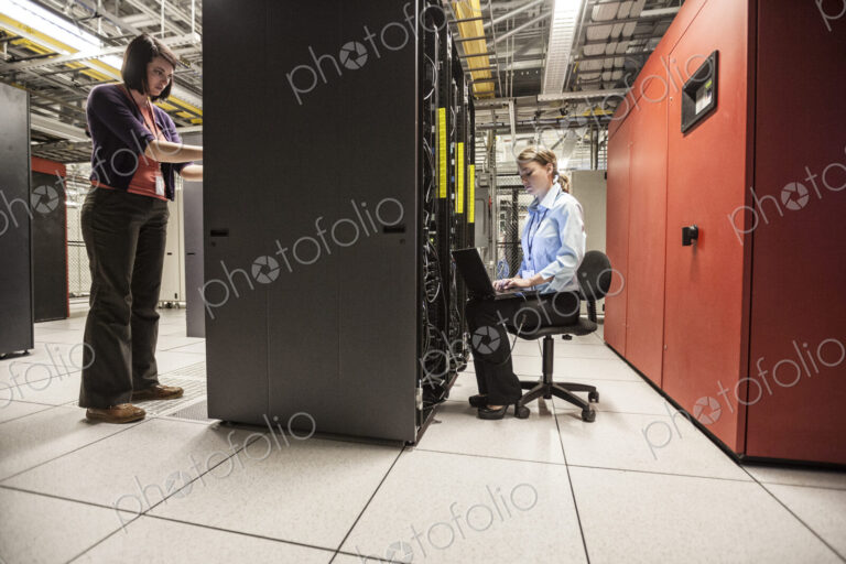 Caucasian women technicians working on computer servers in a server farm.