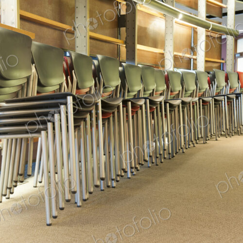 Chairs in an office stacked and lined up prior to a corporate meeting.