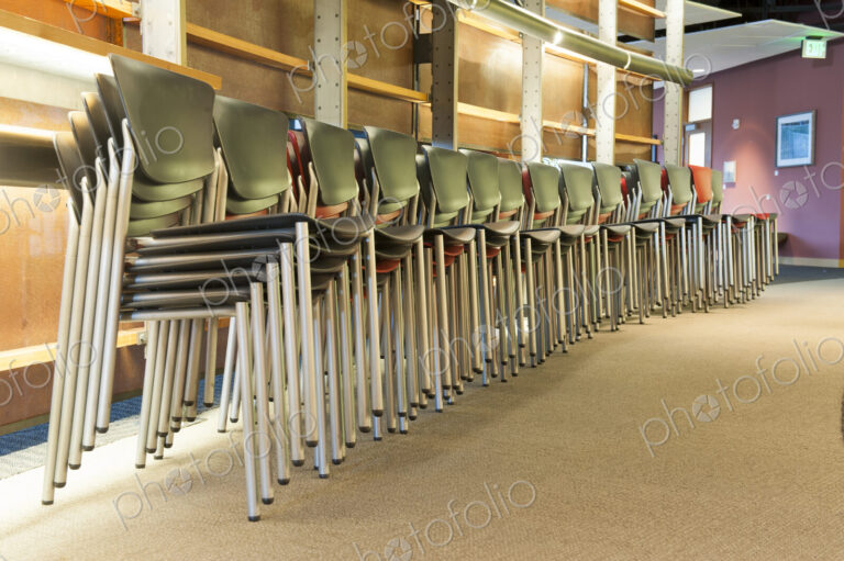 Chairs in an office stacked and lined up prior to a corporate meeting.