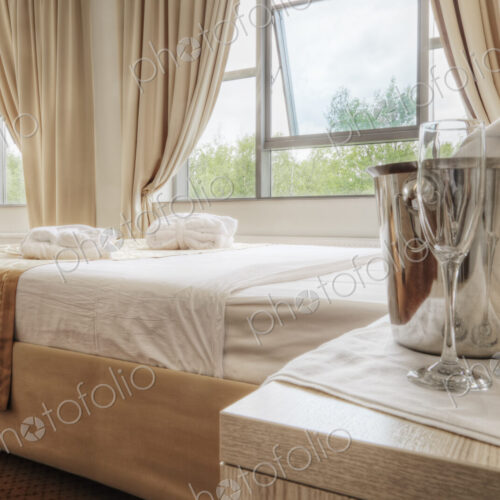 Champagne and glasses by bed in hotel room