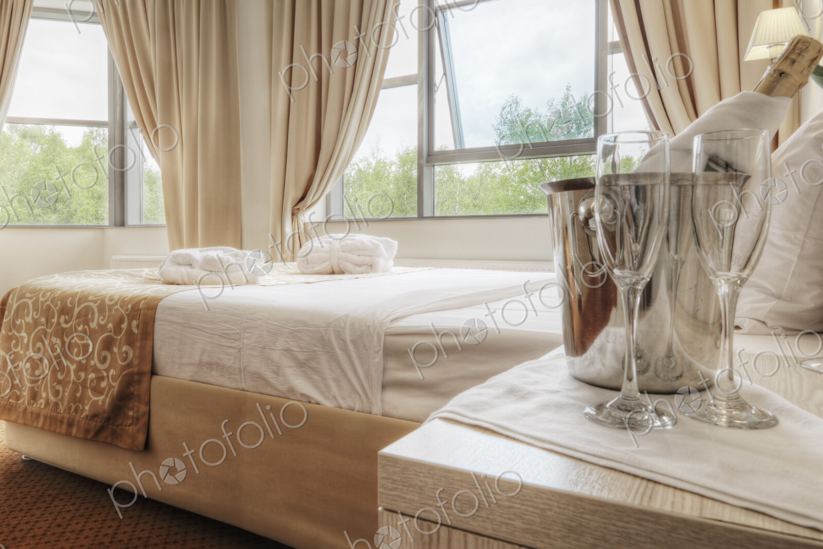 Champagne and glasses by bed in hotel room