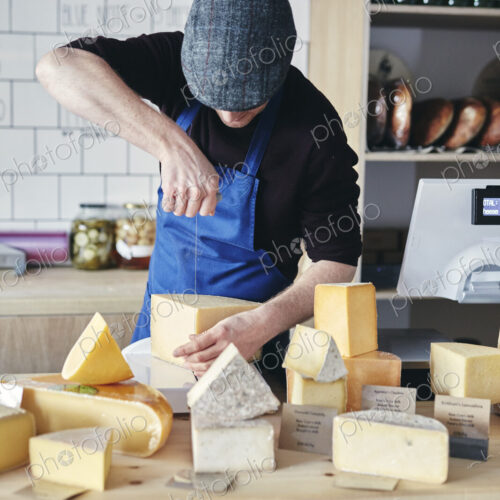 Cheesemonger cutting cheese using cheese wire