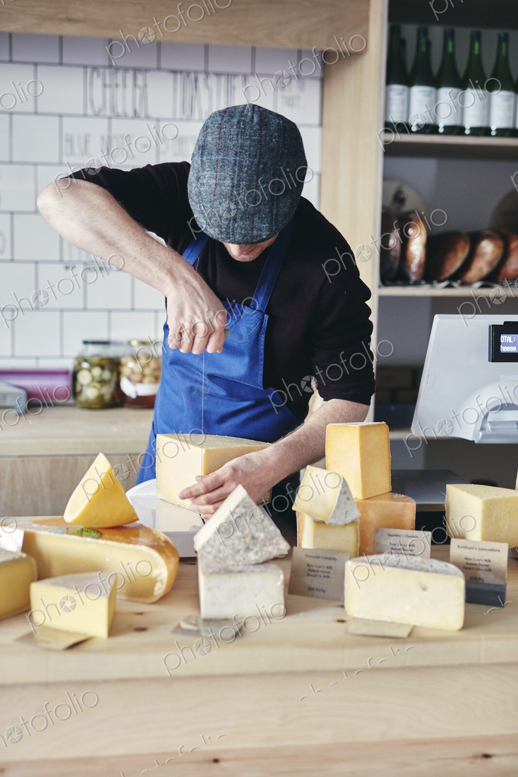 Cheesemonger cutting cheese using cheese wire