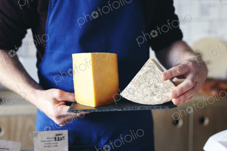 Cheesemonger holding slate displaying two different cheeses