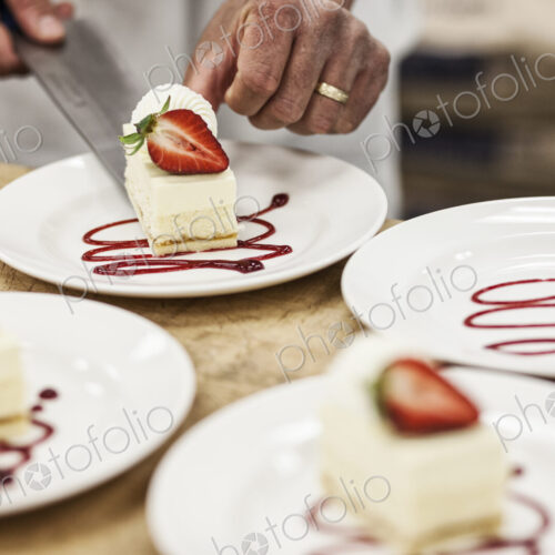 Chef hands placing a layered desert on a plate, presentation of a sweet dish.