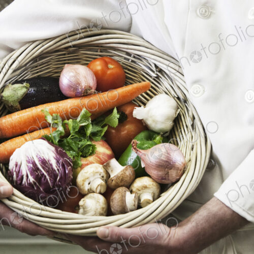 Chef holding a basket of freshly picked vegetables.