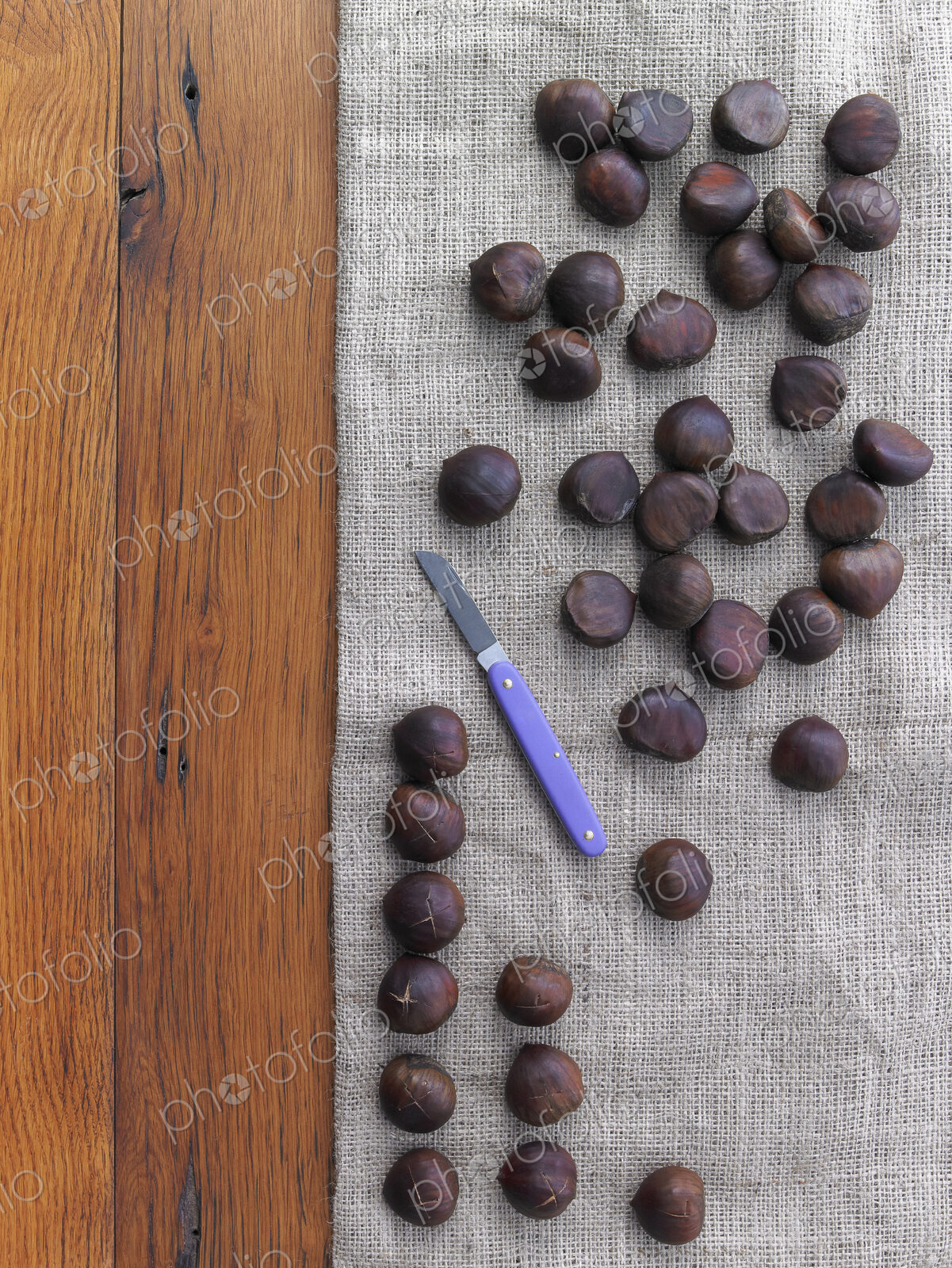 Chestnuts being prepared for roasting. Tabletop, hessian fabric and knife.