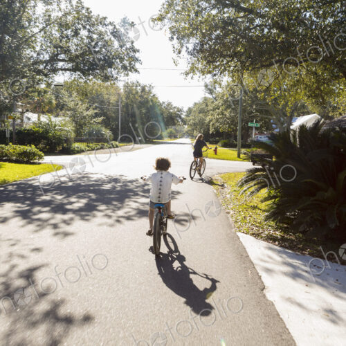 Children, a pre teenager and her brother cycling on a suburban road