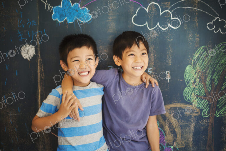 Children in school. Two boys standing with their arms around each other's shoulders by…