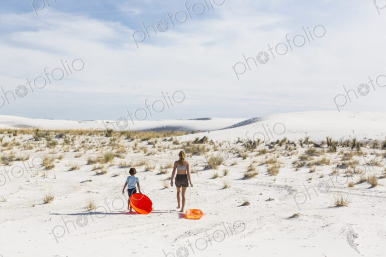 Children pulling sleds, White Sands Nat'l Monument, NM