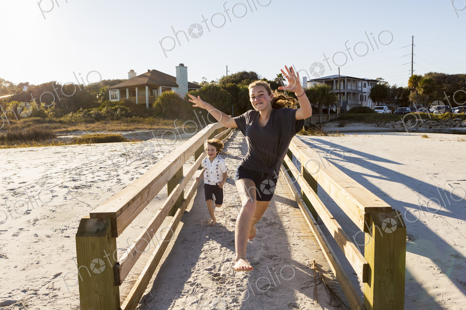 Children running across wooden bridge over sand