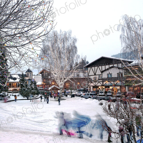 Children running on snowy slope in front of skiing resort buildings.