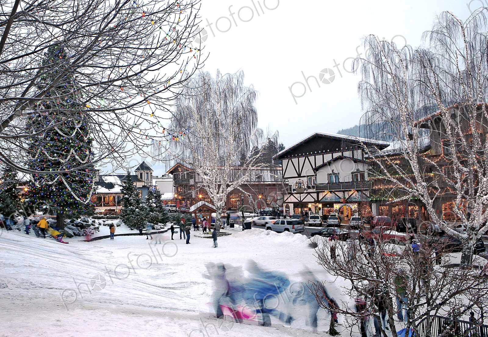Children running on snowy slope in front of skiing resort buildings.