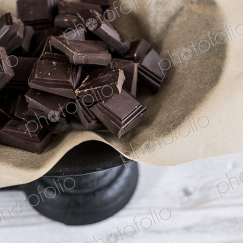 Chocolate pieces on greaseproof paper on a weighing scale. Chocolate pieces on greaseproof paper on a weighing scale.