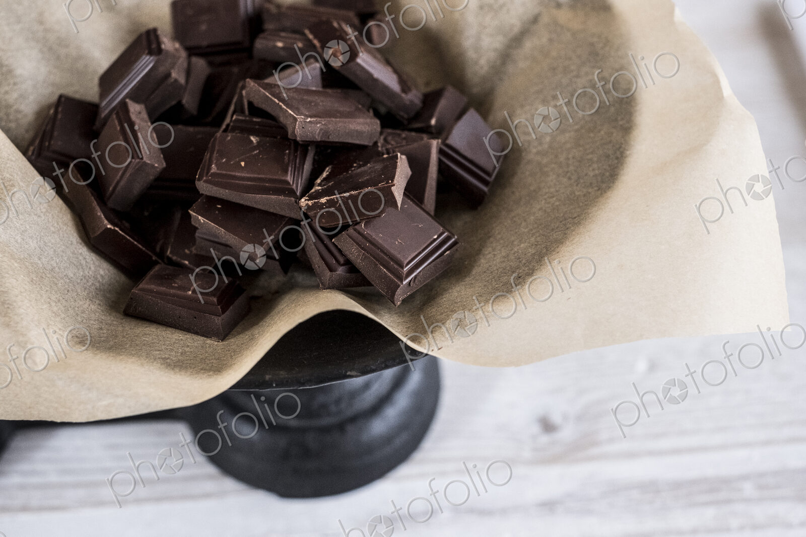Chocolate pieces on greaseproof paper on a weighing scale.