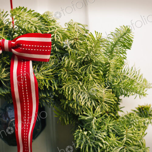 Christmas decorations. A Christmas wreath with a red bow on the front door of a house.