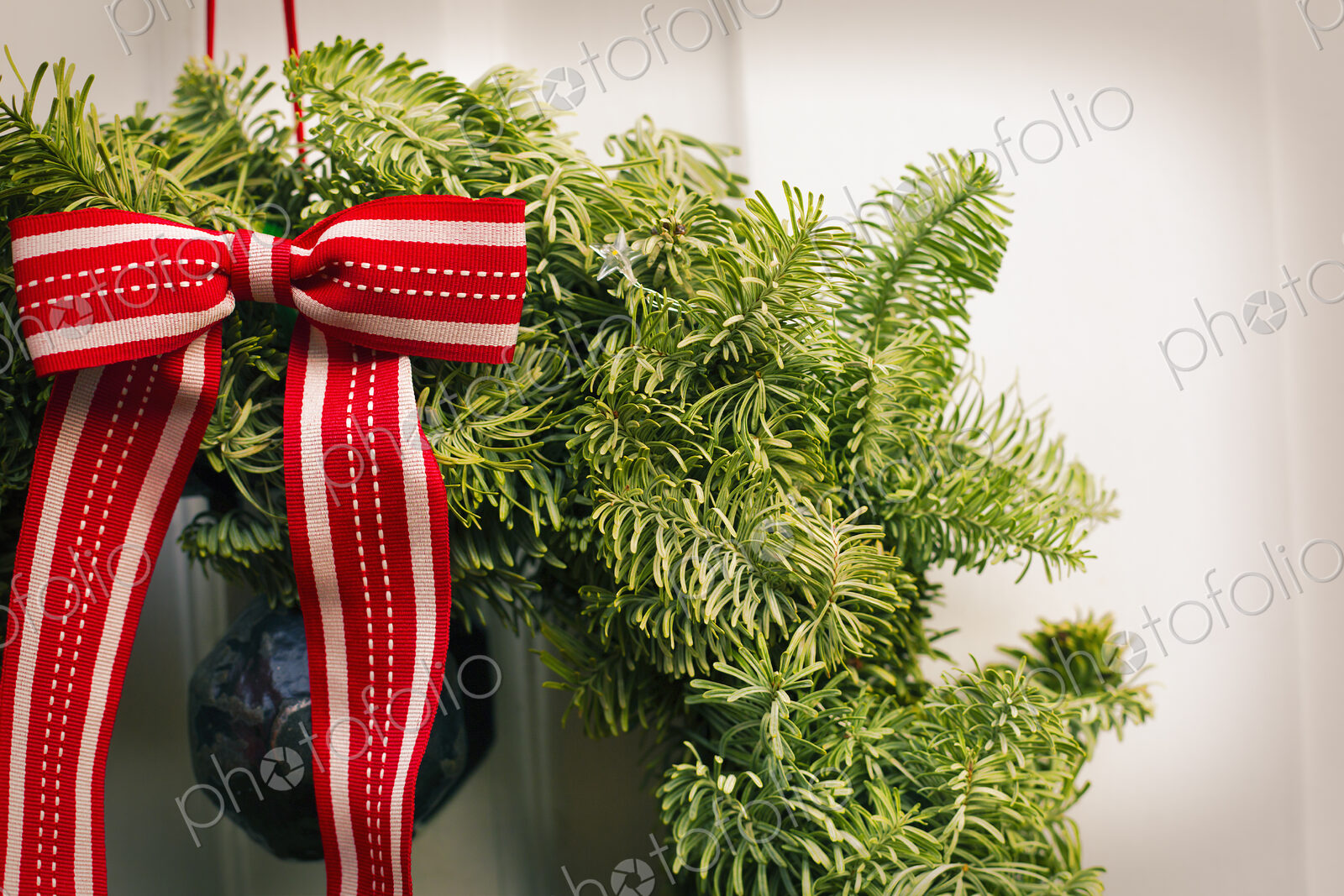 Christmas decorations. A Christmas wreath with a red bow on the front door of a house.