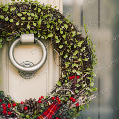 Christmas decorations. A Christmas wreath with a red bow on the front door of a house.