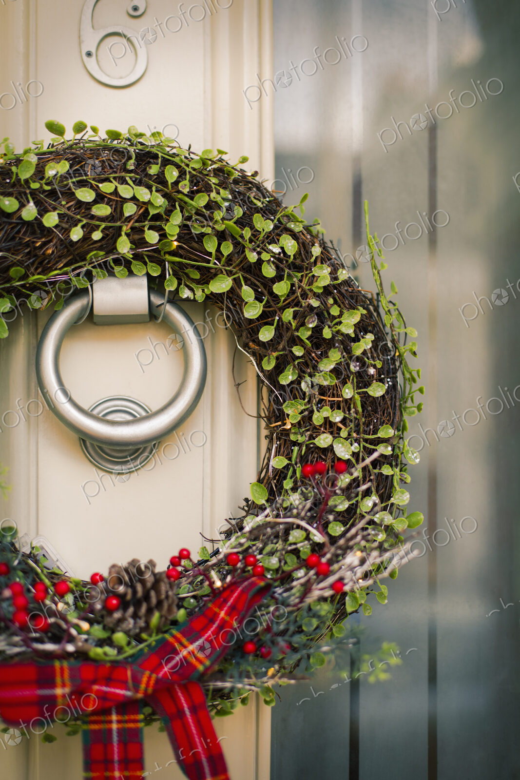 Christmas decorations. A Christmas wreath with a red bow on the front door of a house.