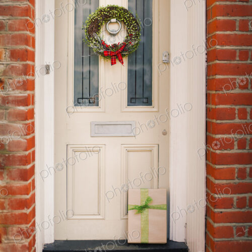Christmas decorations. A Christmas wreath with a red bow on the front door of a house.