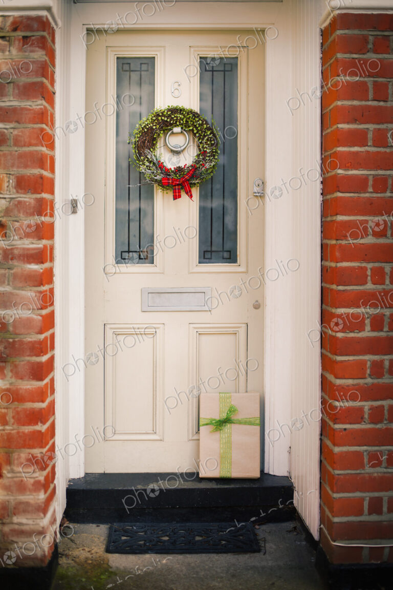 Christmas decorations. A Christmas wreath with a red bow on the front door of a house.