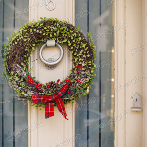 Christmas decorations. A Christmas wreath with a red bow on the front door of a house.
