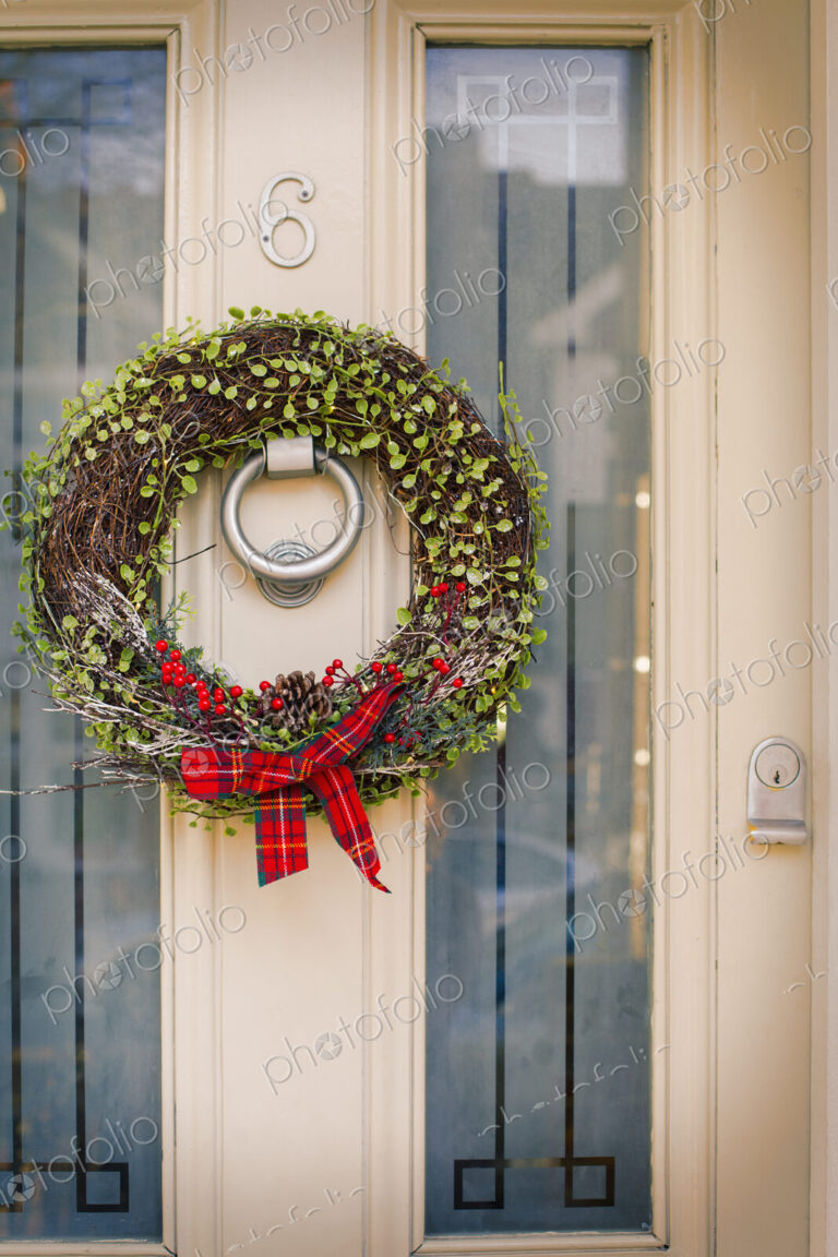 Christmas decorations. A Christmas wreath with a red bow on the front door of a house.