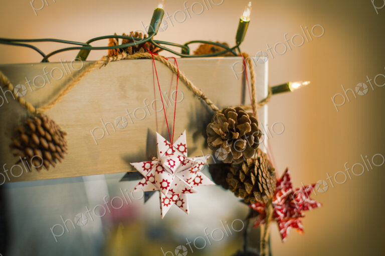 Christmas decorations. Fairy lights, pine cones and paper stars.