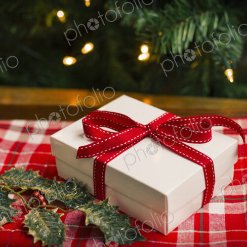 Christmas decorations. Gift box tied with a ribbon and holly leaves. Christmas decorations. Gift box tied with a ribbon and holly leaves.