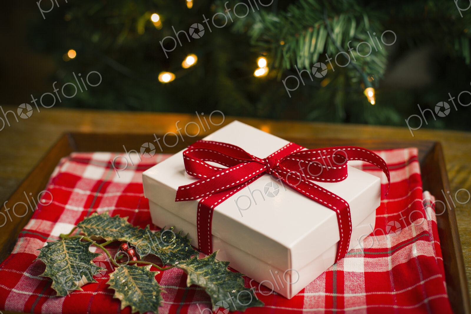Christmas decorations. Gift box tied with a ribbon and holly leaves.