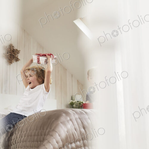 Christmas morning in a family home. A girl holding a present above her head. Christmas morning in a family home. A girl holding a present above her head.