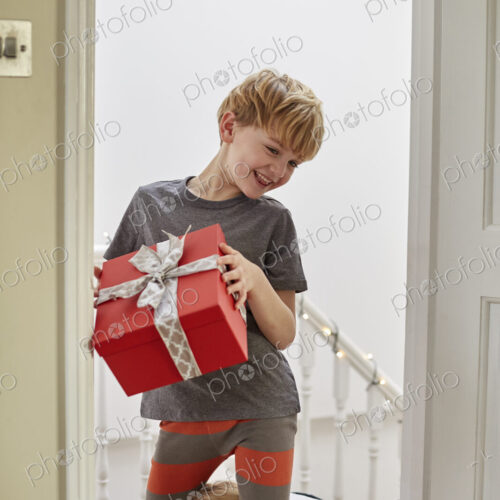 Christmas morning in a family home. Two children on the stairs carrying presents. Christmas morning in a family home. Two children on the stairs carrying presents.