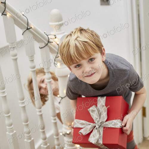 Christmas morning in a family home. Two children on the stairs carrying presents. Christmas morning in a family home. Two children on the stairs carrying presents.