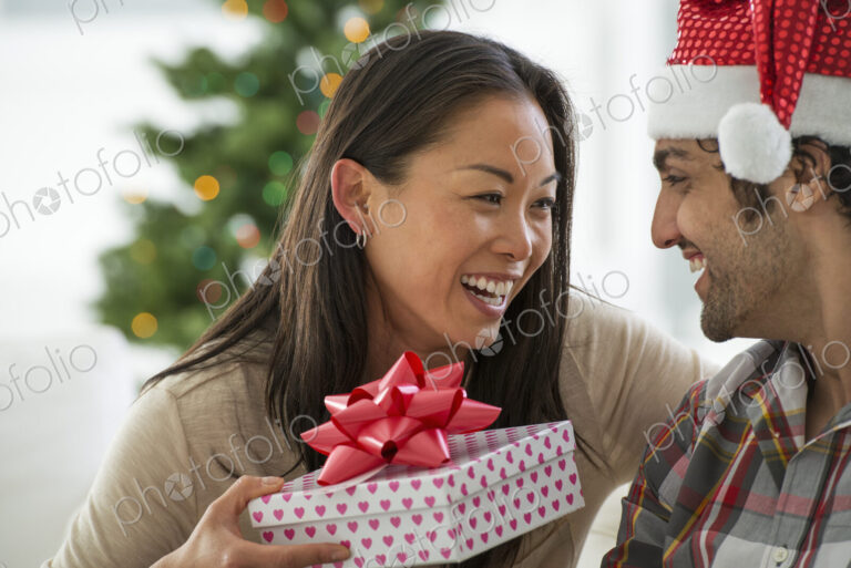 Christmas time. Celebrating the holidays. A man in a Father Christmas hat. At home. A…