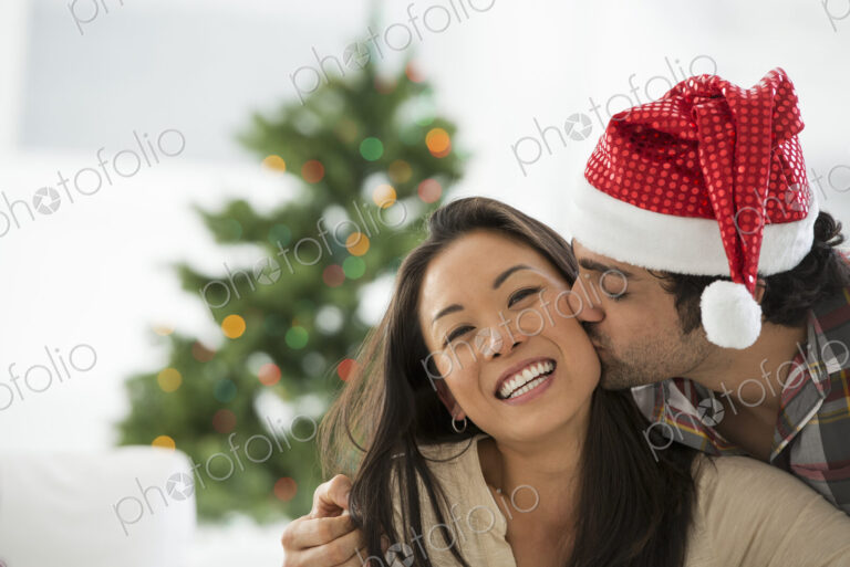 Christmas time. Celebrating the holidays. A man in a Father Christmas hat. At home. A…