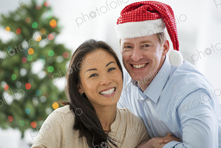 Christmas time. Celebrating the holidays. A man in a Father Christmas hat. At home. A…
