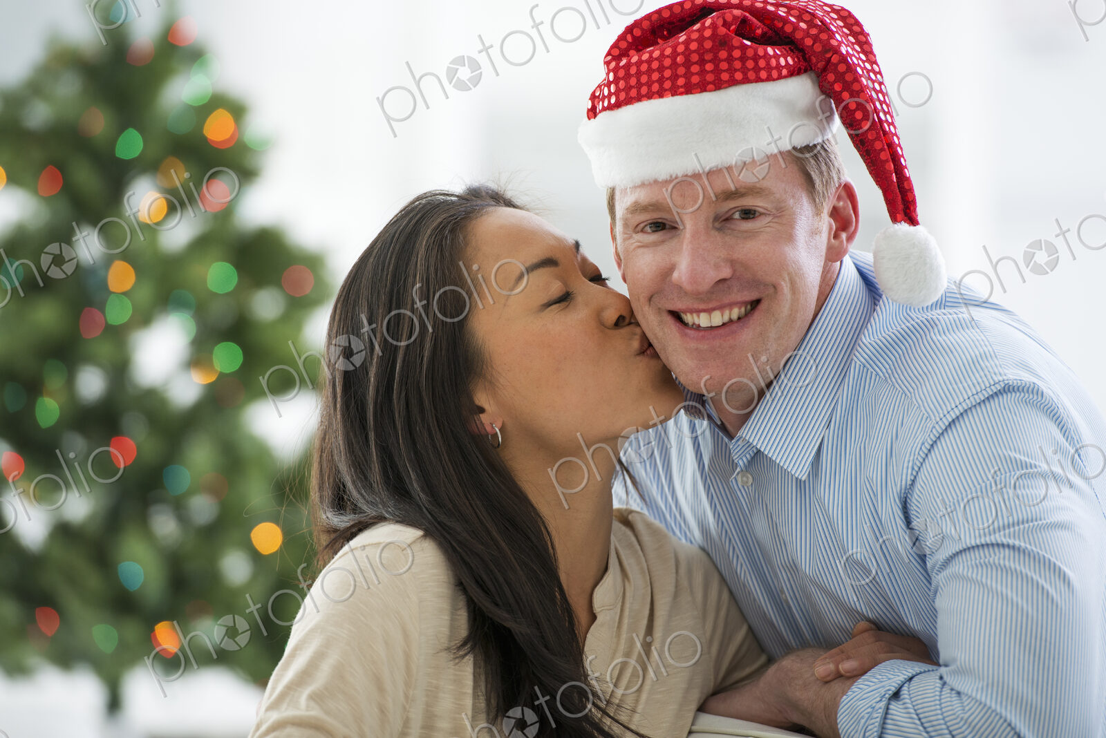 Christmas time. Celebrating the holidays. A man in a Father Christmas hat. At home. A…