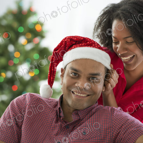 Christmas time. Celebrating the holidays. A man in a Father Christmas hat. At home. A… Christmas time. Celebrating the holidays. A man in a Father Christmas hat. At home. A…