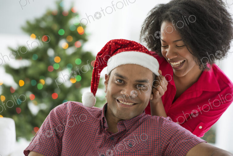 Christmas time. Celebrating the holidays. A man in a Father Christmas hat. At home. A…