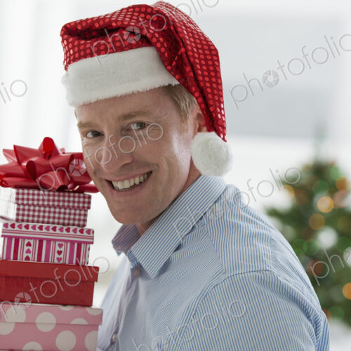 Christmas time. Celebrating the holidays. A man in a Father Christmas hat. At home. A…