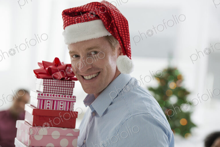 Christmas time. Celebrating the holidays. A man in a Father Christmas hat. At home. A…