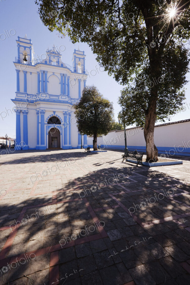 Church in a town square and a shady bench under a tree