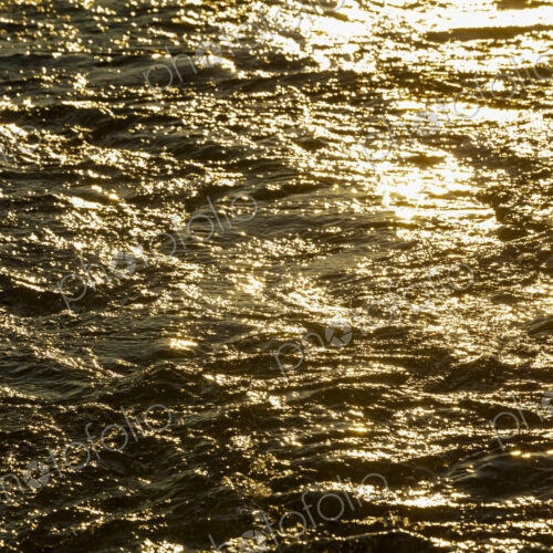 Churned up water, a boat wake and waves on the water surface, reflections of sunlight…