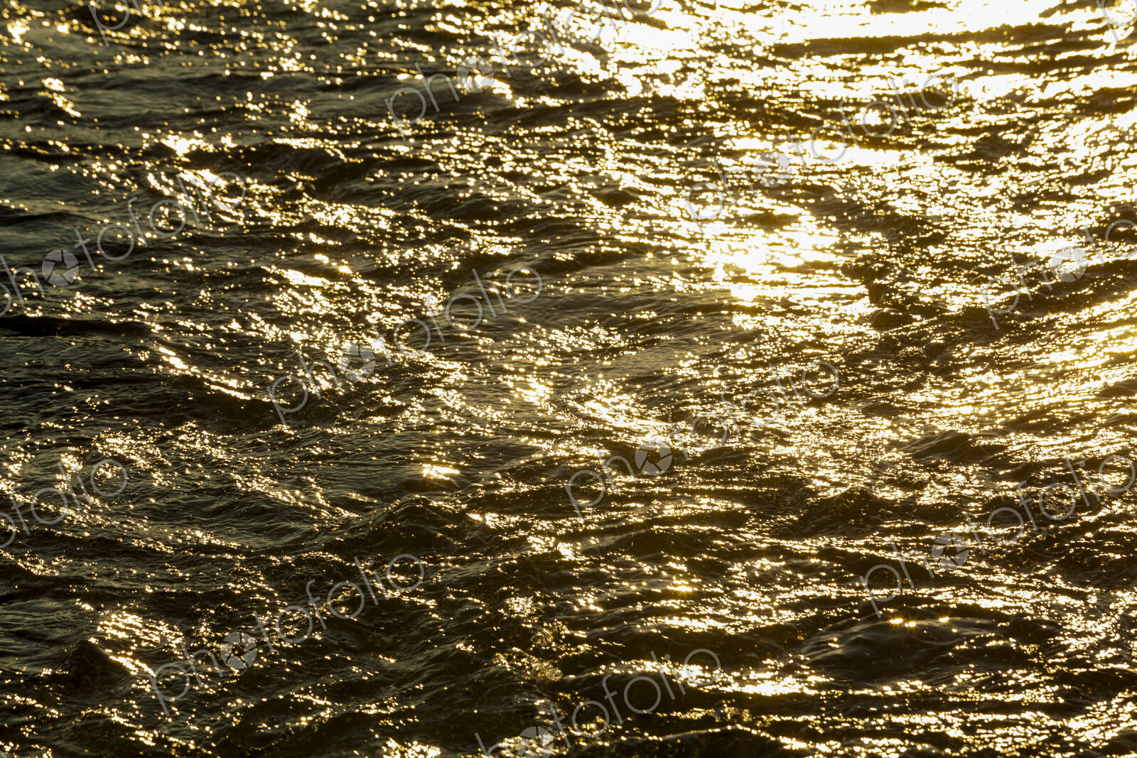 Churned up water, a boat wake and waves on the water surface, reflections of sunlight…
