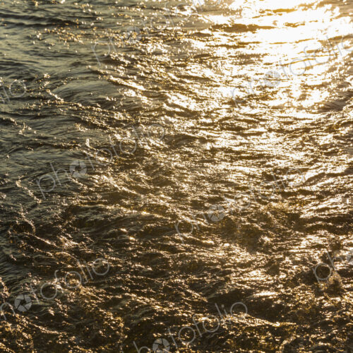 Churned up water with the sun reflecting off the surface.