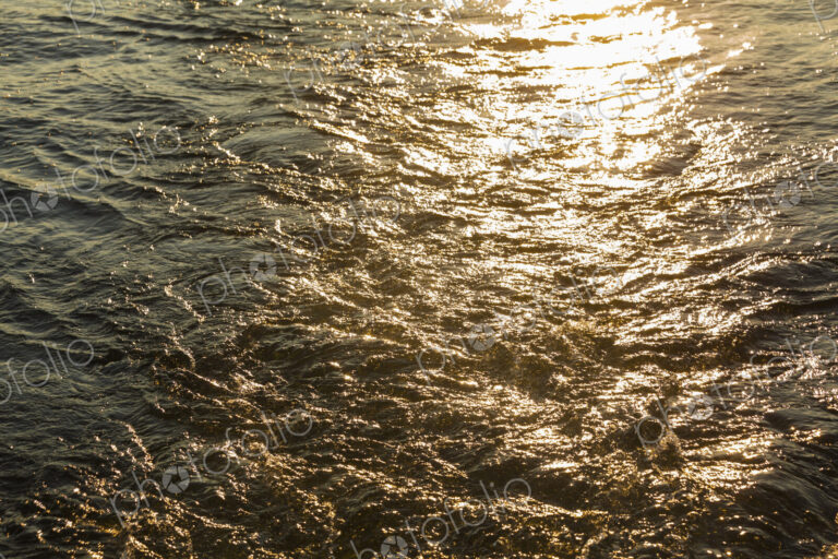 Churned up water with the sun reflecting off the surface.