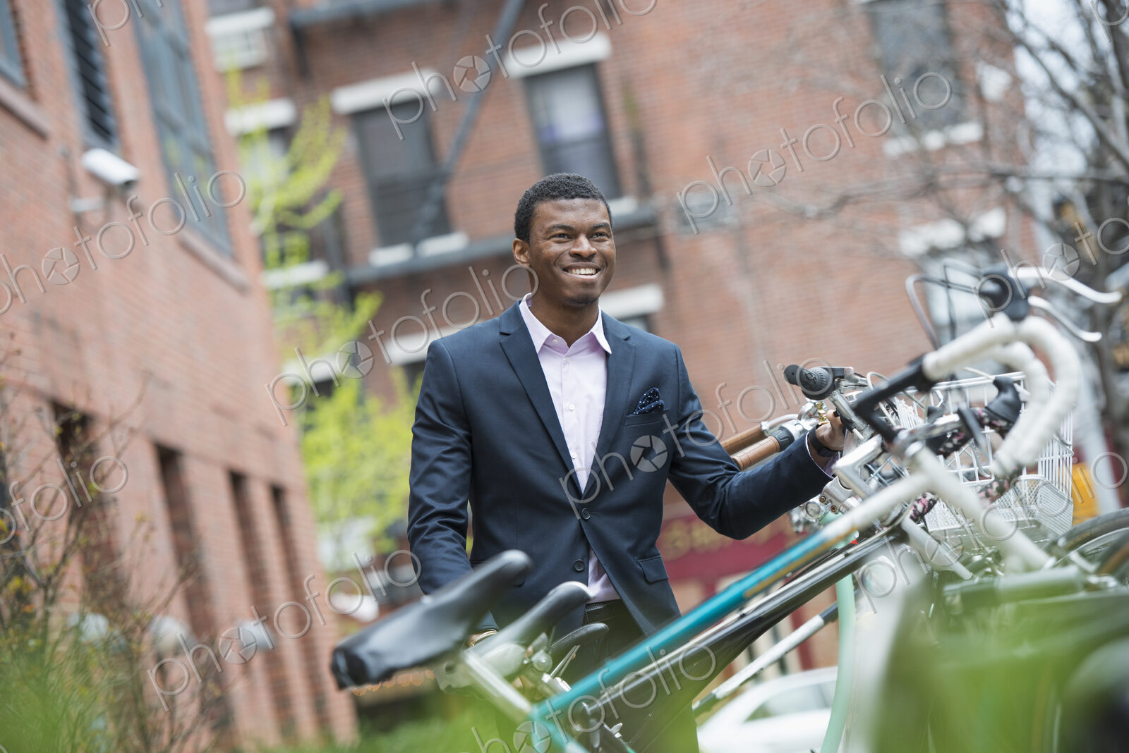 City life in spring. A man in a blue suit, by a bicycle rack in a city park.
