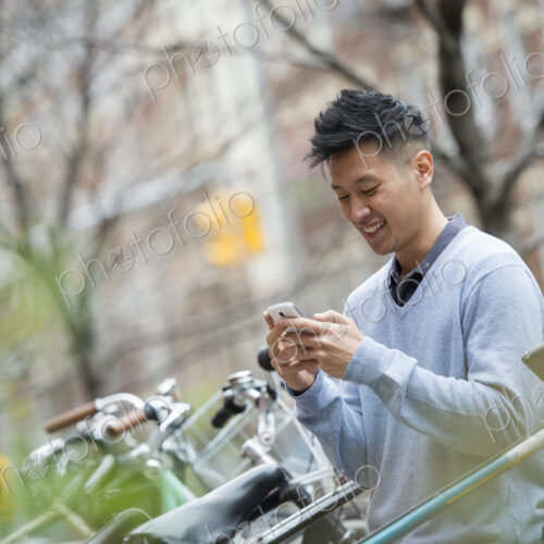City life in spring. A man in a blue sweater by a row of parked bicycles. Checking his… City life in spring. A man in a blue sweater by a row of parked bicycles. Checking his…