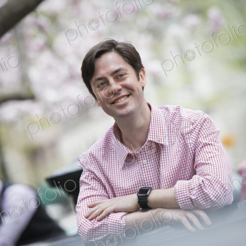 City life in spring. A man sitting outdoors in a city park. Looking at the camera and…